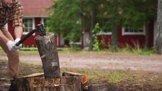 Strong man splitting a tough wooden log with an axe. Slow motion 4K ProRes 422 footage of successful manual labor