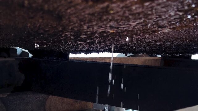 Rusty metal surface with water drops dripping from edge, showing corrosion, moisture and aging texture in industrial environment, ideal for decay, weather, and grunge themes