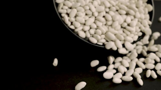 Black_bowl_and_scattered_white_beans_on_black_background_4k_10bit_120fps