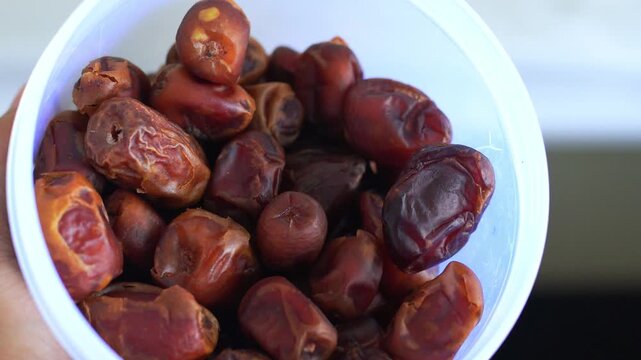 White bowl filled with dark brown dried dates fruit. Perfect for food blogs, recipes, healthy eating articles, and ramadanthemed designs.