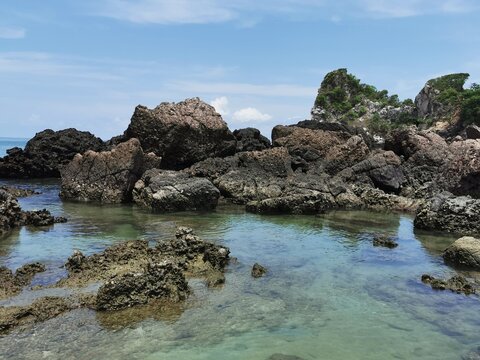 Close-up of jagged rock formations along the clear tropical seashore in Thailand