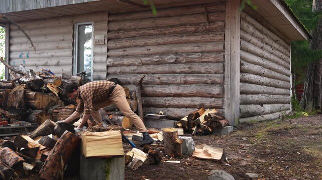 Efficient wood splitting in one hit. Strong man chopping firewood fast in front of a log house. 4K slow motion.