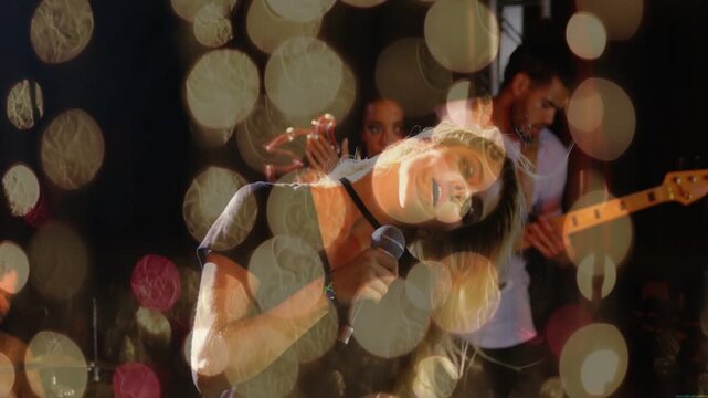 Lead singer revealing bokeh as camera shifting, singing into mic, band playing music to engage fans