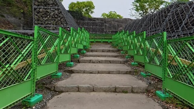 POV walking up stone stairs through a narrow passage surrounded by construction fences