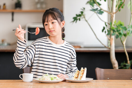 A young girl in elementary school who dislikes vegetables, is a picky eater, and cannot eat tomatoes.