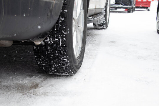 雪道を走行する車とスタッドレスタイヤのクローズアップ（冬の交通・安全イメージ）