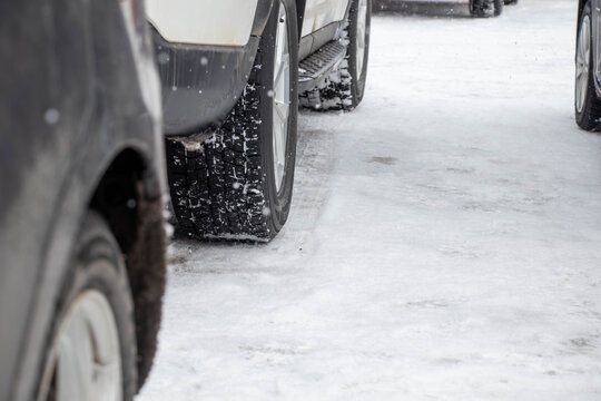 雪道を走行する車とスタッドレスタイヤのクローズアップ（冬の交通・安全イメージ）