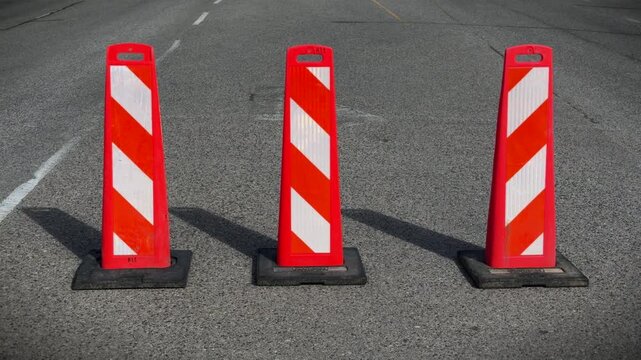 Three large pylons on a multilane road blocking a turning lane on a sunny day