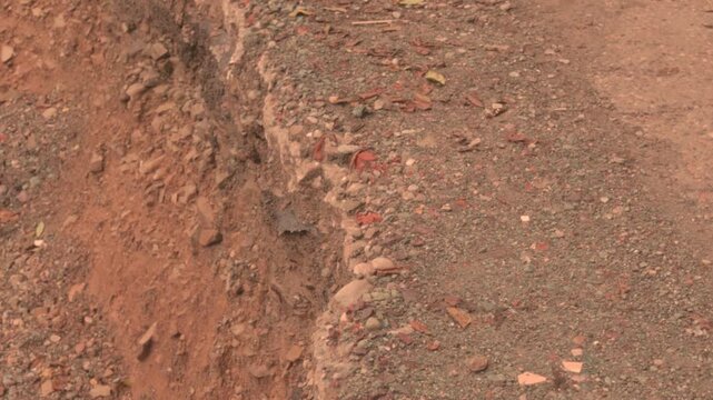 Landslide on road edge with falling dirt natural disaster damage scene