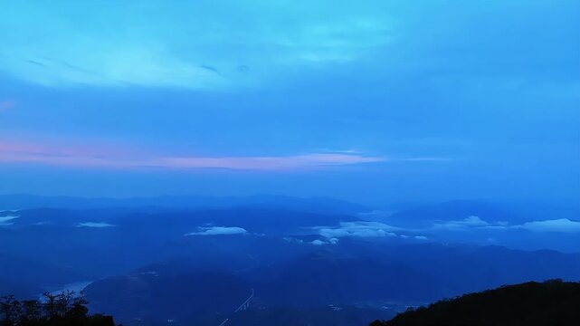 Stunning timelapse of blue twilight and flowing sea of clouds over high altitude mountain peaks in China.