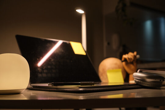 Workspace with laptop, lamp, and other items in a dim study area at night