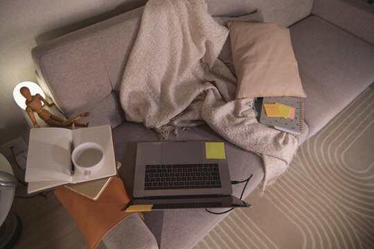 Modern sofa transformed into a comfortable workspace with laptop, notebooks, and coffee