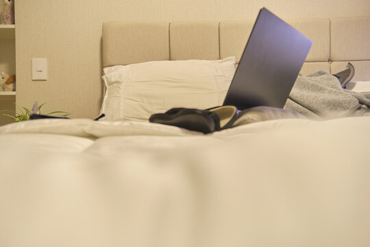 Person working from home, comfortably using a laptop on a bed in cozy bedroom