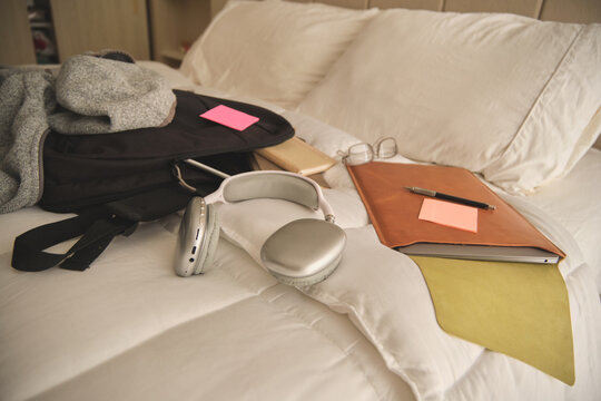 Student belongings and school supplies resting on a clean white bed, creating a study area