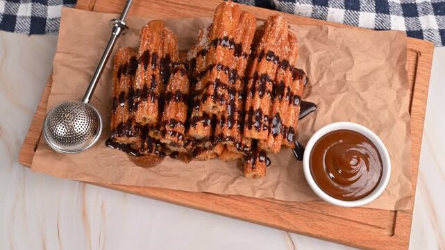 Crispy homemade churros with sugar and melted chocolate on a wooden board