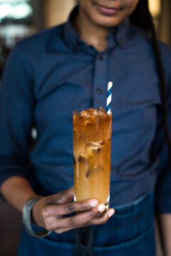 Person in Blue Shirt Holding Iced Coffee with Milk