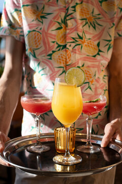 Server Holding Tray of Three Bright Cocktails