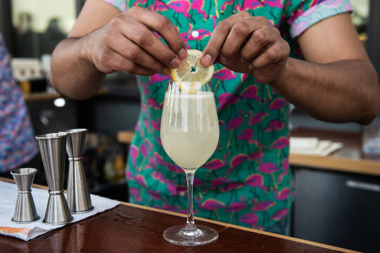 Bartender Garnishes Yellow Cocktail with Lemon