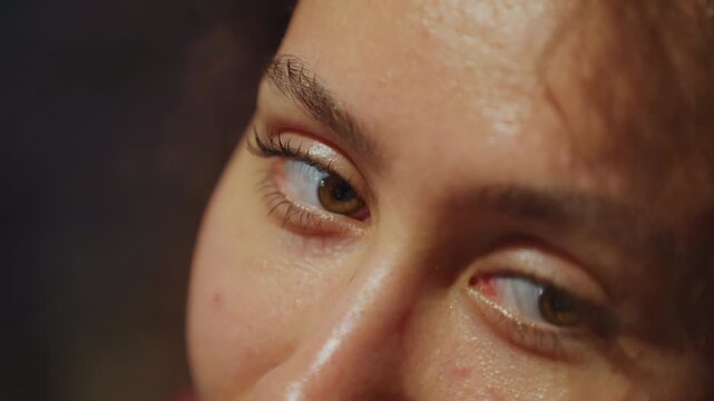 Closeup face looking sideways subtle smile, dewy skin and glistening eyelid, cheek catching warm highlights, curly tendrils framing profile, minor smile suggesting mischief, roles include storyteller