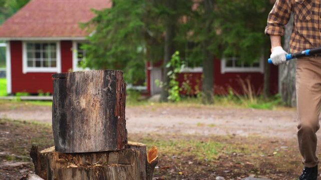Strong man splitting a tough wooden log with an axe. Slow motion 4K ProRes 422 footage of successful manual labor