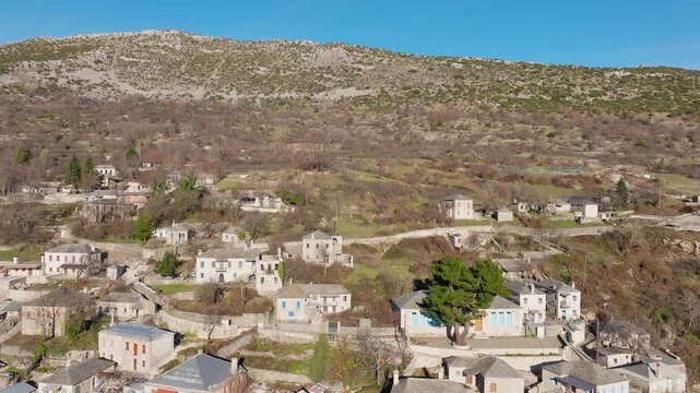 Reveal drone shot of Kalarites village in Tzoumerka under bright sunshine, showcasing traditional stone architecture