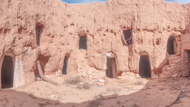 Panorama: Traditional troglodyte houses carved into rock in Matmata, Tunisia. Ancient underground dwellings in arid desert landscape, historic Berber architecture and cultural heritage site