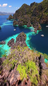 Cinematic FPV drone flight over turquoise waters and limestone cliffs at Twin Lagoon, Coron, Philippines. Aerial view of tropical lagoon with boats and crystal clear sea.
