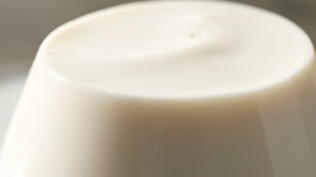Extreme close-up of smooth creamy dessert surface, highlighting the luxurious texture of vanilla panna cotta or pudding