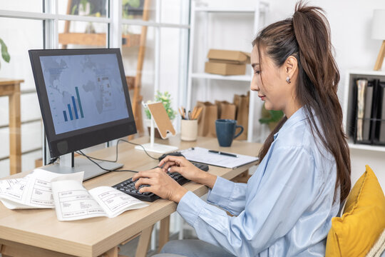 Ecommerce, order, management, online seller types at desktop computer in home office, handling customer requests and backend workflow while preparing shipping paperwork for small business operation