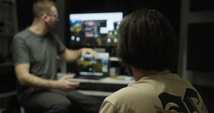 Man explaining software or a website on a computer screen to a colleague. Concept of teamwork, IT support and workplace communication.