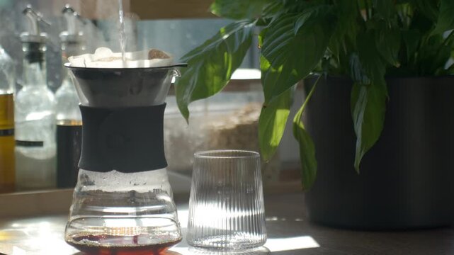 Hot water pouring into paper filter dripper during manual coffee brewing at home. Concept of pour over preparation morning ritual and specialty coffee lifestyle.