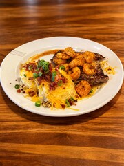 Fototapeta premium Ai Generates Premium steak and shrimp combo with loaded mashed potatoes on elegant plate, styled with warm lighting on wooden table, ideal for gourmet dining, luxury food, and restaurant promotion vis
