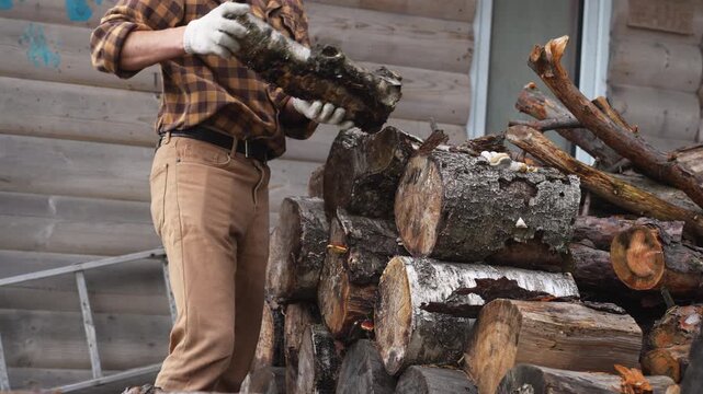 Close up of a man throwing firewood logs aside. Slow motion 4K ProRes 422 footage of manual labor at countryside.