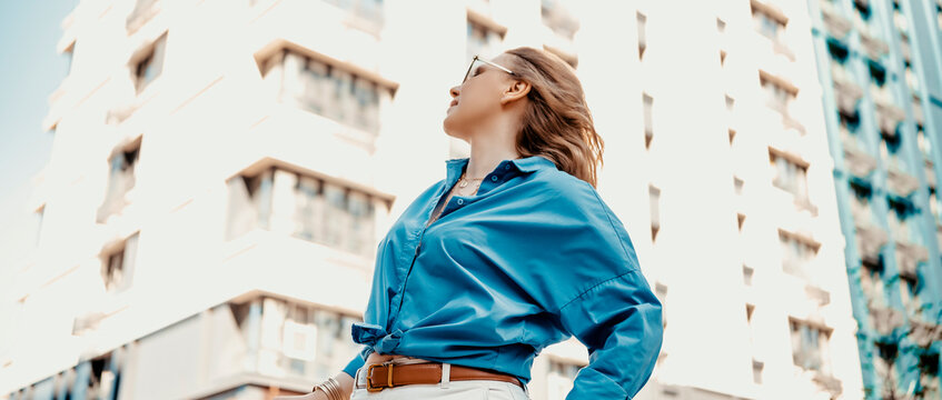Woman in blue shirt on bright overexposed city background. Minimalism and high key photography style.