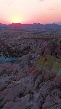 Vertical video. Goreme, Nevsehir, Turkey. Aerial view of multicolored rock layers in Red Valley at sunset, showing red, orange and yellow hues.. Aerial View, Departure of the camera, MasterShots. Ric