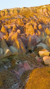 Vertical video. Goreme, Nevsehir, Turkey. Inspiring aerial view of Devrent Valley with magical rock formations and golden sunset colors.. Aerial View. Rich colors