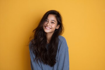 Fototapeta premium asian teenage girl with long wavy hair smiling brightly on solid background youthful positivity portrait