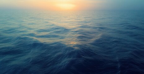 Obraz premium Peaceful open ocean at sunrise with gentle waves and warm golden light on the distant horizon, evoking calm and serenity