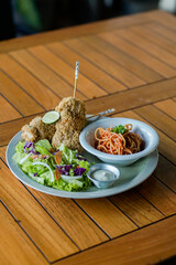 Crispy fried chicken served with spaghetti and fresh salad on plate over wooden table. Clean composition with copy space for text. Casual dining concept. © MithaArini