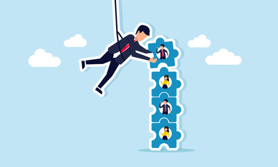 Fototapeta premium Businessman hanging on rope arranging puzzle pieces with businessman image illustration concept of building strong team for business management