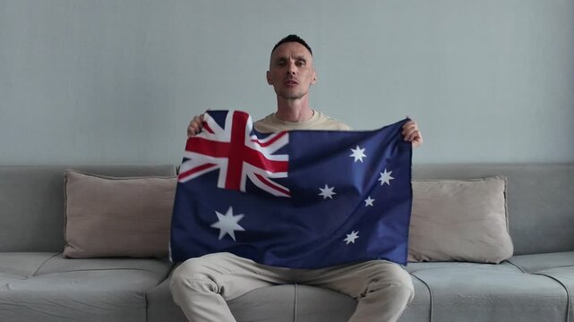An Australian football fan watches football and supports his favorite team while holding the Australian flag
