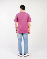 Obraz premium The back of a man wearing a plain purple t-shirt and blue jeans is seen with his hands at his sides, against a white background.