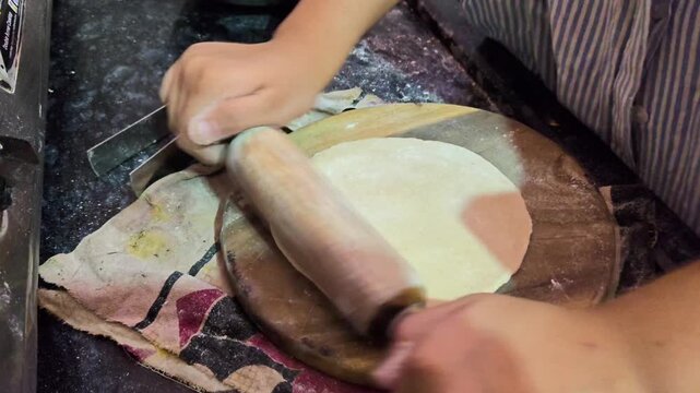 Rolling dough ball into a flat circle for roti. Indian flatbread