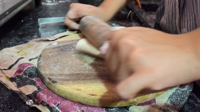 Rolling dough ball into a flat circle for roti. Indian flatbread