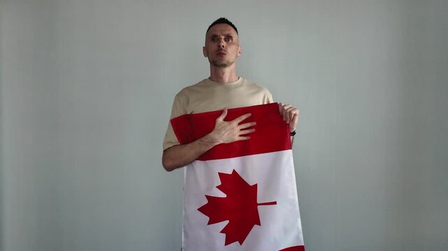 A patriotic man proudly sings the Canadian national anthem while holding a Canadian flag. A sports fan holds a Canadian flag