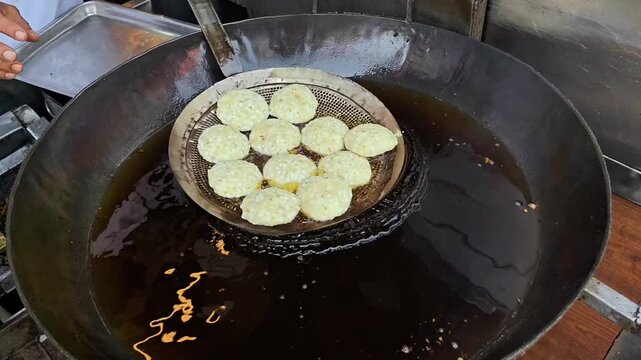 Deep frying crispy sabudana vada in boiling oil. Indian street food