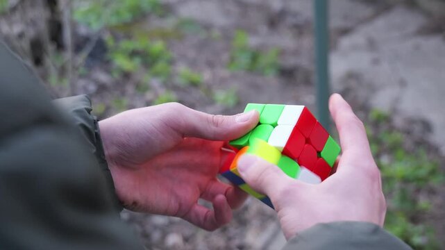 Close-up video of two hands solving a Rubik cube, showing finger movements and rotations in natural light with focused composition. 2026