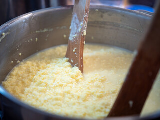 Cooking traditional Easter egg cheese (hrudka) in a pot, curdling eggs mixture close to completion, close-up food preparation. © Marek
