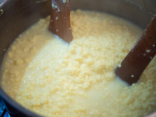Cooking traditional Easter egg cheese (hrudka) in a pot, curdling eggs mixture close to completion, close-up food preparation. © Marek