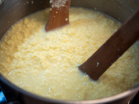 Cooking traditional Easter egg cheese (hrudka) in a pot, curdling eggs mixture close to completion, close-up food preparation.